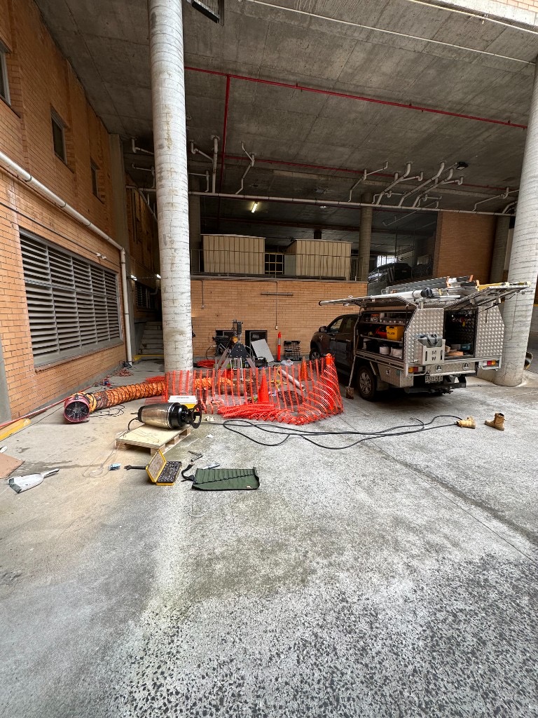 Mayfair Plumbing commercial pump repair site at Queen Victoria Apartments in Rose Park, with service ute, temporary pump and confined-space ventilation set up in the undercroft car park